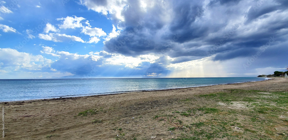 sun rays breaking through the clouds on the sea sandy beach. beauty in nature. dark storm clouds cover the sky, the rays of the sun form beautiful light streaks