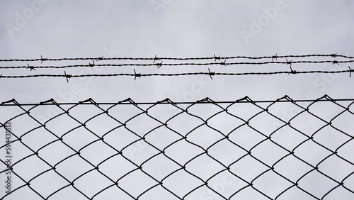 metal grate with barbed wire against sky