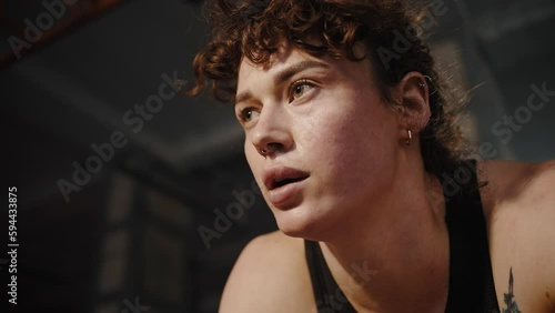 Headshot female athlete weightlifter relaxing after heavy training in smokey gym