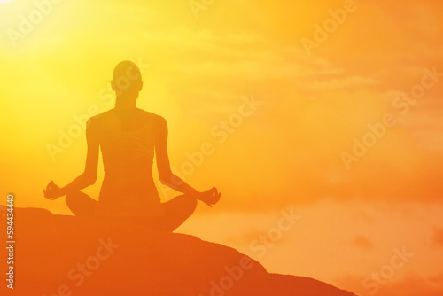Woman silhouette mediating outdoors at sunset 