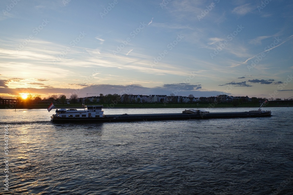 Panorama von Düsseldorf mit Blick über den Rhein auf ein Frachtschiff im Sonnenuntergang 