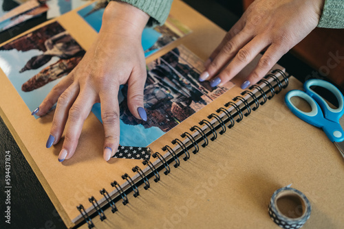 Vászonkép Close-up image of the hands of an unrecognizable middle-aged woman making sure that the piece of washi tape over a photo in her handmade kraft travel album is securely attached