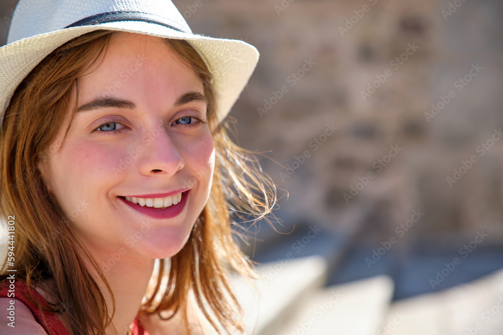 close-up portrait of smiling blue eyes redhead young girl in white hat looking at camera
