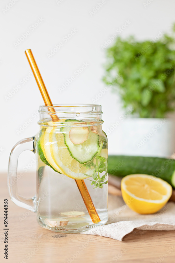 Fototapeta premium Infused water with cucumber, lemon and ginger in glass bottle on wooden table. Diet, detox, healthy eating, weight loss concept
