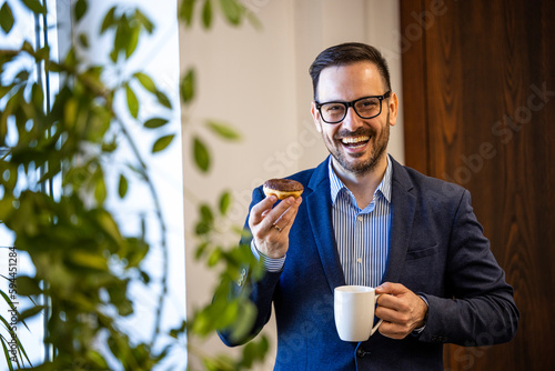 Portrait of businessman having a work break enjoying coffee and donuts. photo