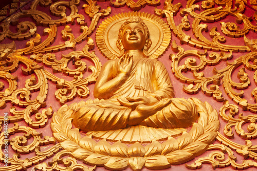 Laos, Luang Prabang. Golden relief carving of Buddha.