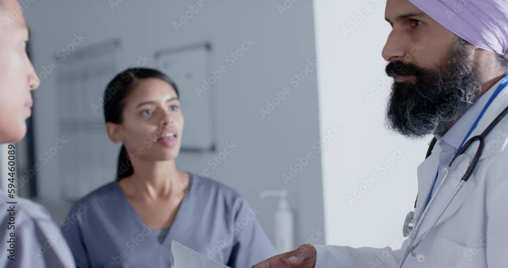Diverse doctors and nurses talking in corridor at hospital, in slow motion Diverse doctors and nurses talking in corridor at hospital, in slow motion