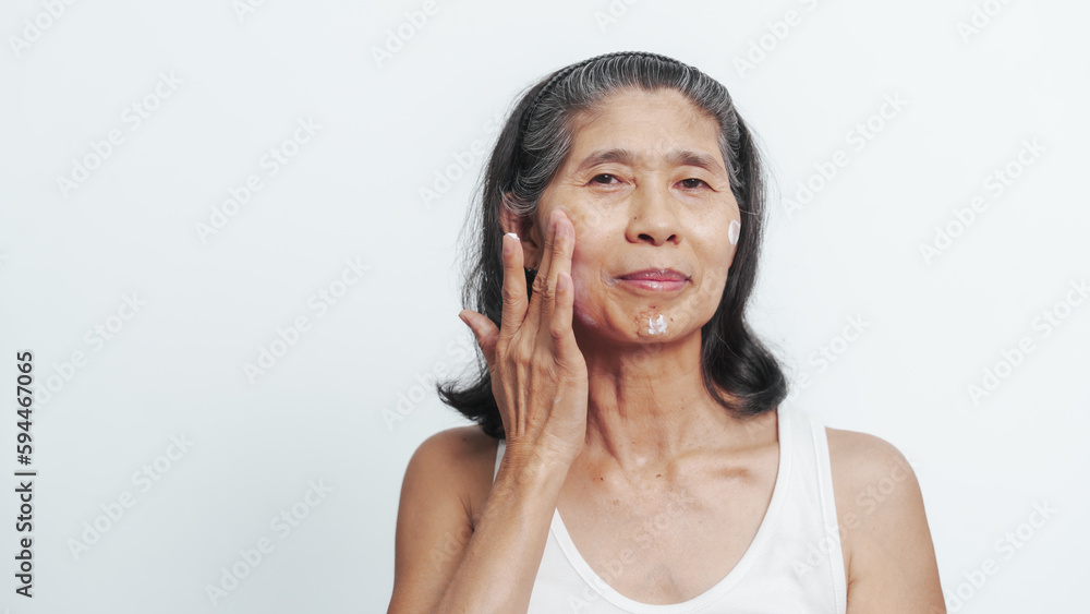 Close up face of female elderly mature older asian chinese housewife applies anti aging facial cream on face, old skincare treatment Close up face of female elderly mature older asian chinese housewife applies anti aging facial cream on face, old skincare treatment