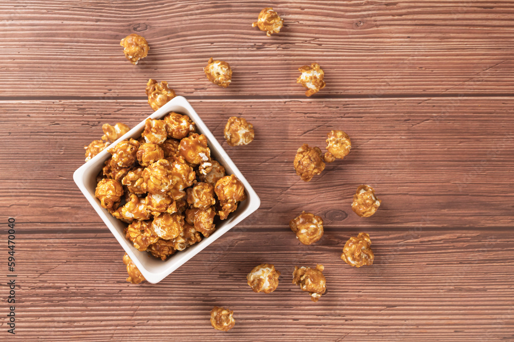 Top view
Caramel popcorn on square bowl on wooden table background. Top view
Caramel popcorn on square bowl on wooden table background.