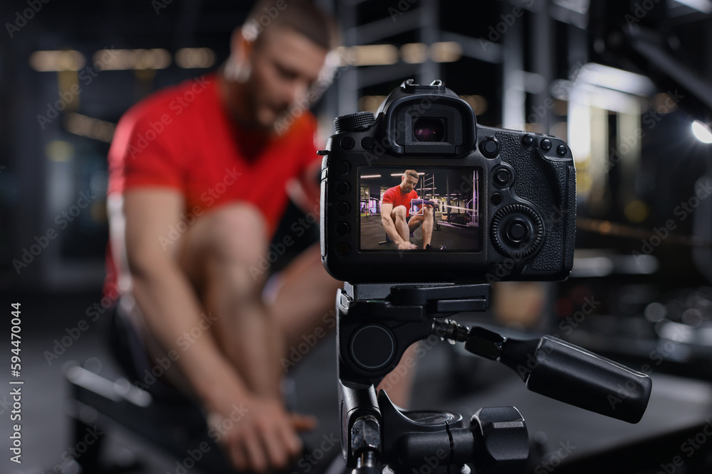 Man recording workout at gym, focus on camera. Online fitness trainer Man recording workout at gym, focus on camera. Online fitness trainer