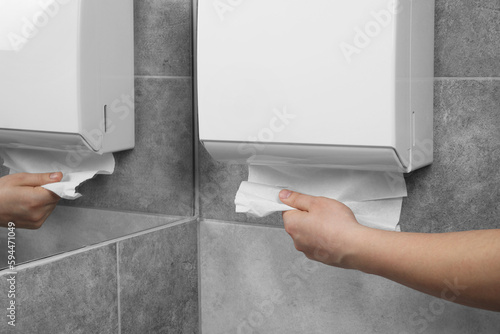 Woman taking new fresh paper towels from dispenser in bathroom, closeup, Space for text photo