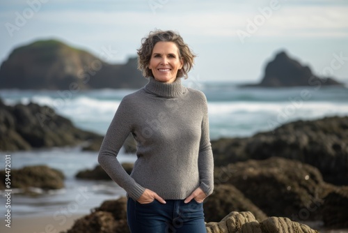 Portrait of smiling woman standing with hands in pockets at the beach