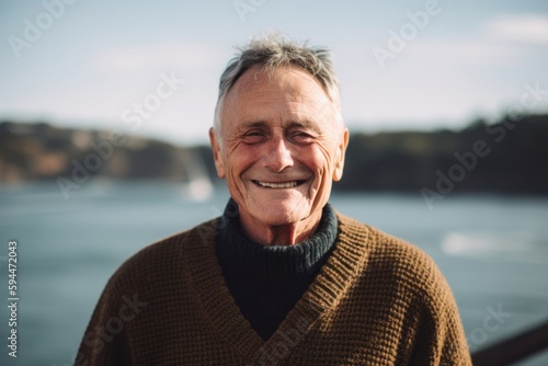 Portrait of a smiling senior man in a sweater on the background of the river