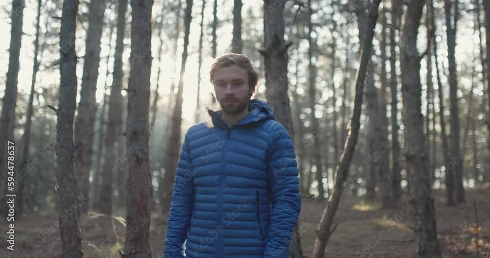 Portrait of a trail runner man standing in the woods. Sun shining through trees in a forest on sunset. Slowmotion video. Portrait of a trail runner man standing in the woods. Sun shining through trees in a forest on sunset. Slowmotion video.