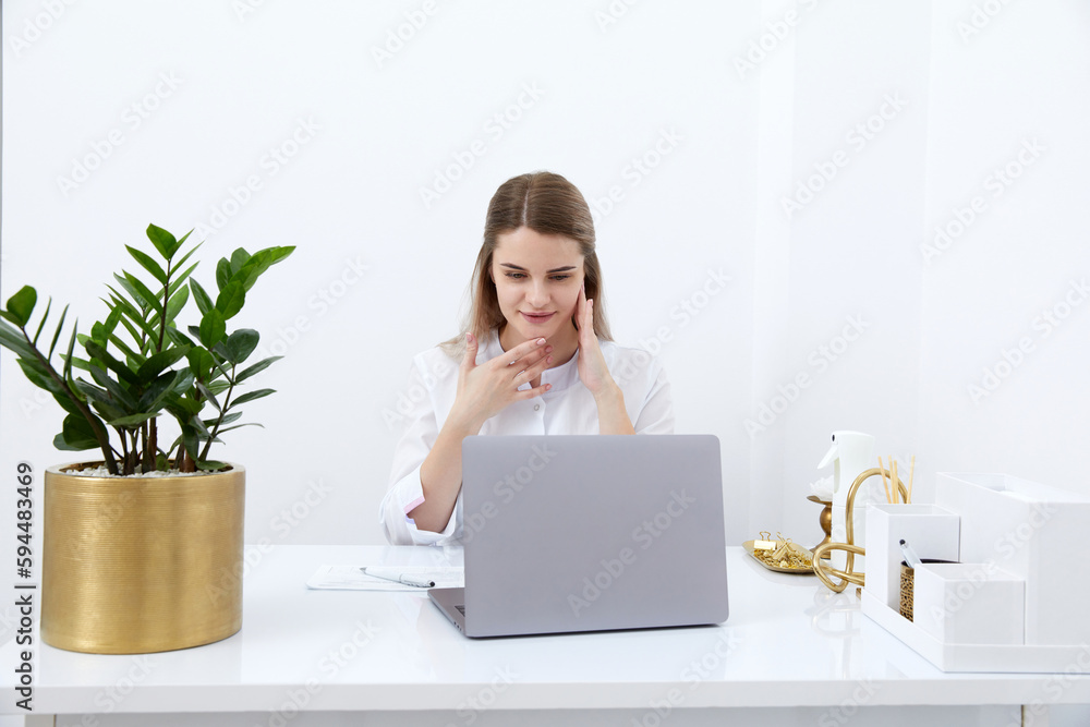 Portrait of female doctor talking to online patient on laptop screen sitting at clinic office desk giving online consultation for domestic health treatment