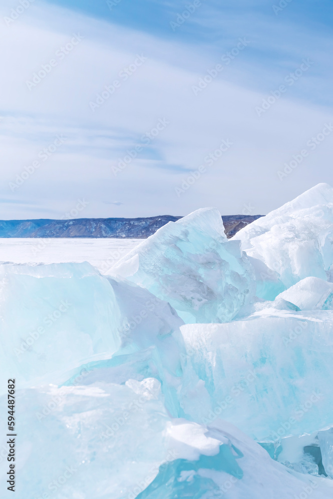Winter landscape with ice hummocks sparkling in the sun and mountains of Baikal in Siberia at sunset. vertical