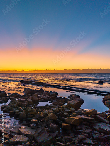 Sunrise over the sea and rocky Inlet with clear skies and a low cloudbank © Merrillie