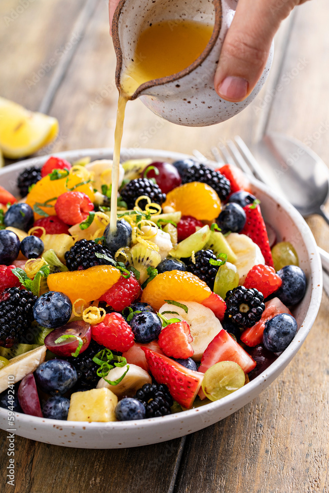 Fruit salad on a wooden table with berries and honey dressing Fruit salad on a wooden table with berries and honey dressing