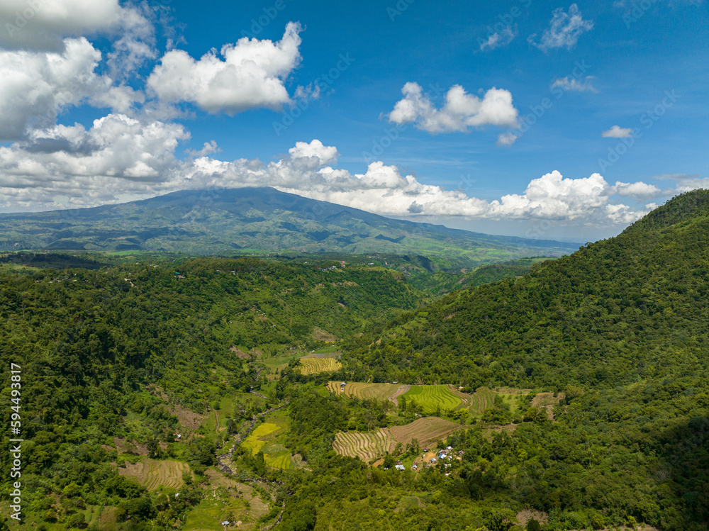 Obraz premium Aerial view of mountain slopes with rainforest and a mountain valley with farmland. Negros, Philippines