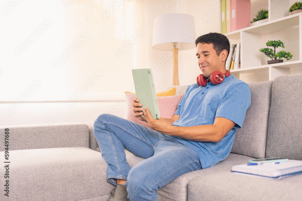 Happy man using digital tablet sitting on the sofa Happy man using digital tablet sitting on the sofa