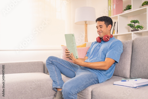 Happy man using digital tablet sitting on the sofa