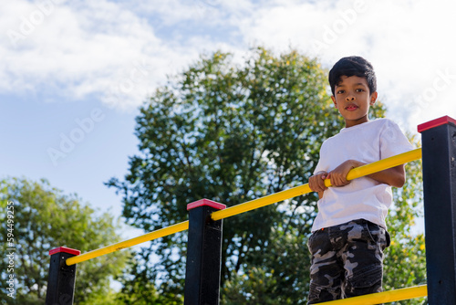 Young boy enjoying playing at the playground in the park.