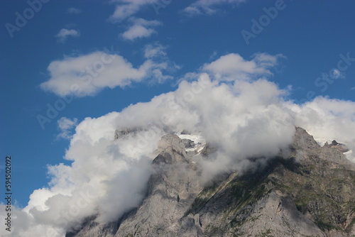 Mountain peak from the mountain range of the swiss alps during summer, touched by the clouds. © Emad Alkhuja