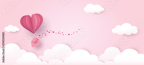 Hot air balloon made of heart origami flies above the clouds in the pink sky with love letter filled with many hearts.  Paper cut design for love, Valentine's Day, Mother's Day, wedding background.