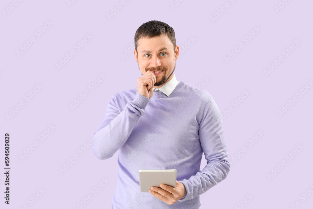 Handsome man with tablet computer biting nails on lilac background Handsome man with tablet computer biting nails on lilac background