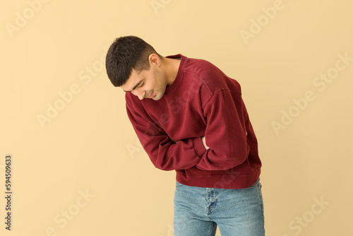 Young man with appendicitis on beige background © Pixel-Shot