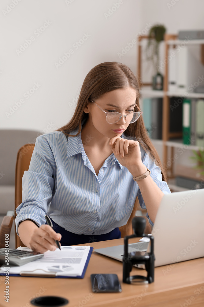 Female accountant working with laptop at table in office Female accountant working with laptop at table in office