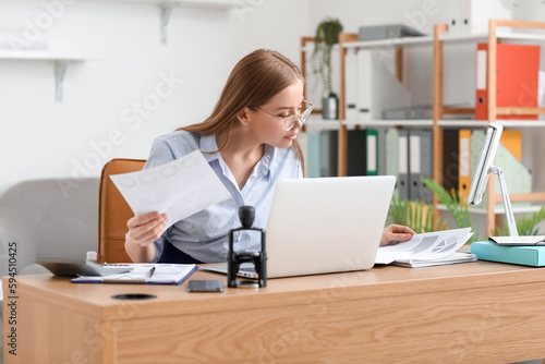 Female accountant working with documents at table in office