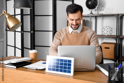 Handsome man using laptop c...