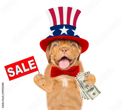 Happy Mastiff puppy wearing like Uncle Sam holds dollars USA and shows signboard with labeled "sale". isolated on white background © Ermolaev Alexandr