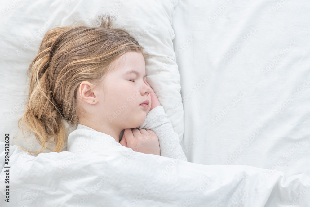 Cute little girl sleeps on the bed at home. Top down view. Empty space for text Cute little girl sleeps on the bed at home. Top down view. Empty space for text