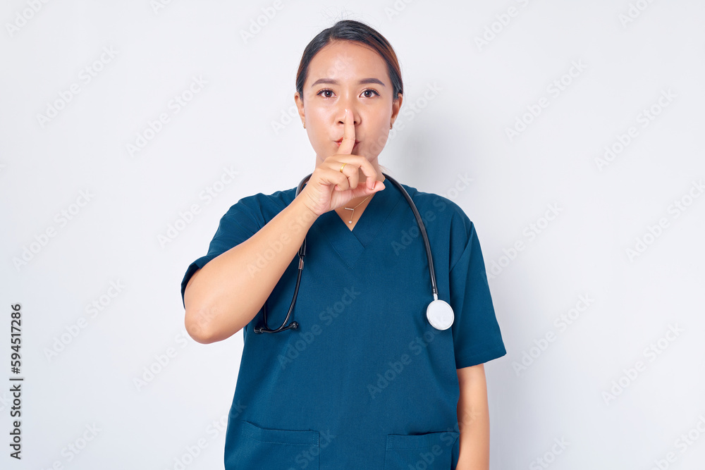 Serious young Asian female nurse working wearing a blue uniform shows silence gestures isolated on white background. Healthcare medicine concept Serious young Asian female nurse working wearing a blue uniform shows silence gestures isolated on white background. Healthcare medicine concept