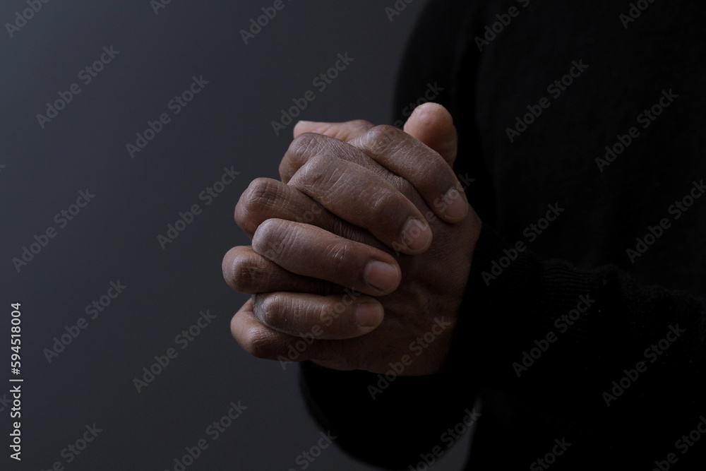 man praying to god with hands together on dark background stock photo