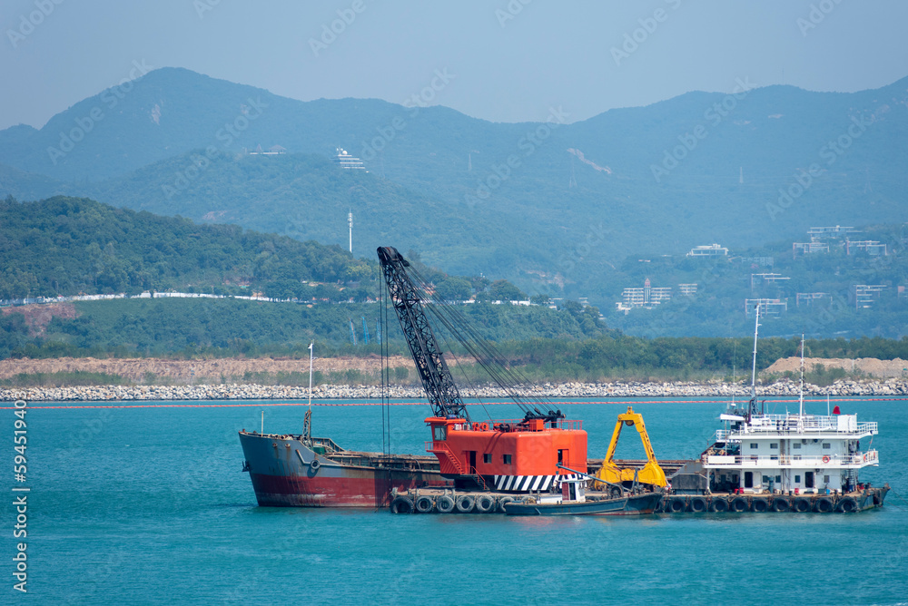 Floating crane working as a dredger near Chinese sea coast.