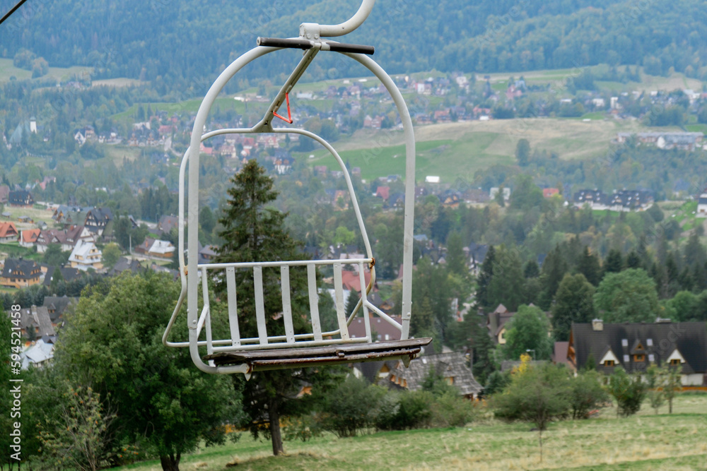 Ski Lift snowy mountain autumn forest with chair lift At The Ski Resort in Zakopane Poland. Holidays Vacation sport and outdoor activities tourism cable car empty seat grass field in green forest on Ski Lift snowy mountain autumn forest with chair lift At The Ski Resort in Zakopane Poland. Holidays Vacation sport and outdoor activities tourism cable car empty seat grass field in green forest on