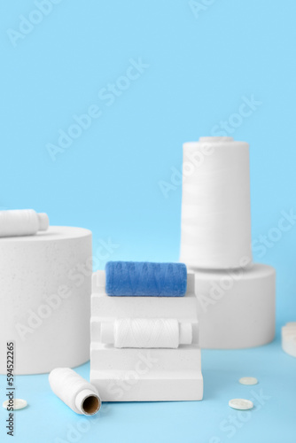 Podiums with thread spools and buttons on blue background