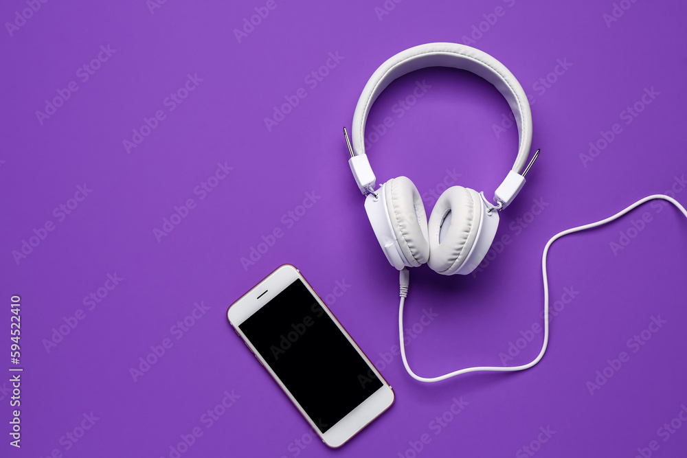 Mobile phone with headphones on purple background Mobile phone with headphones on purple background