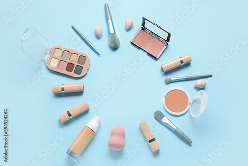 Frame made of decorative cosmetics, brushes and sponges on blue background