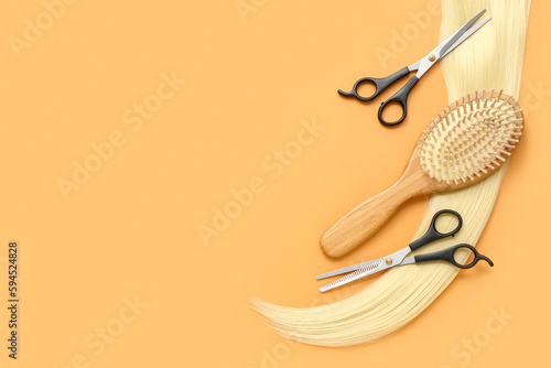 Hair strand with brush and scissors on orange background