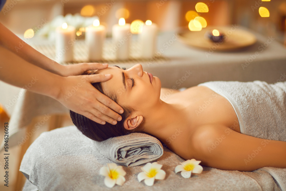 Beautiful woman enjoying facial massage in spa salon. Serene brunette girl lying on massage bed with closed eyes and relaxing. Beauty, spa treatment, skin care, wellbeing Beautiful woman enjoying facial massage in spa salon. Serene brunette girl lying on massage bed with closed eyes and relaxing. Beauty, spa treatment, skin care, wellbeing
