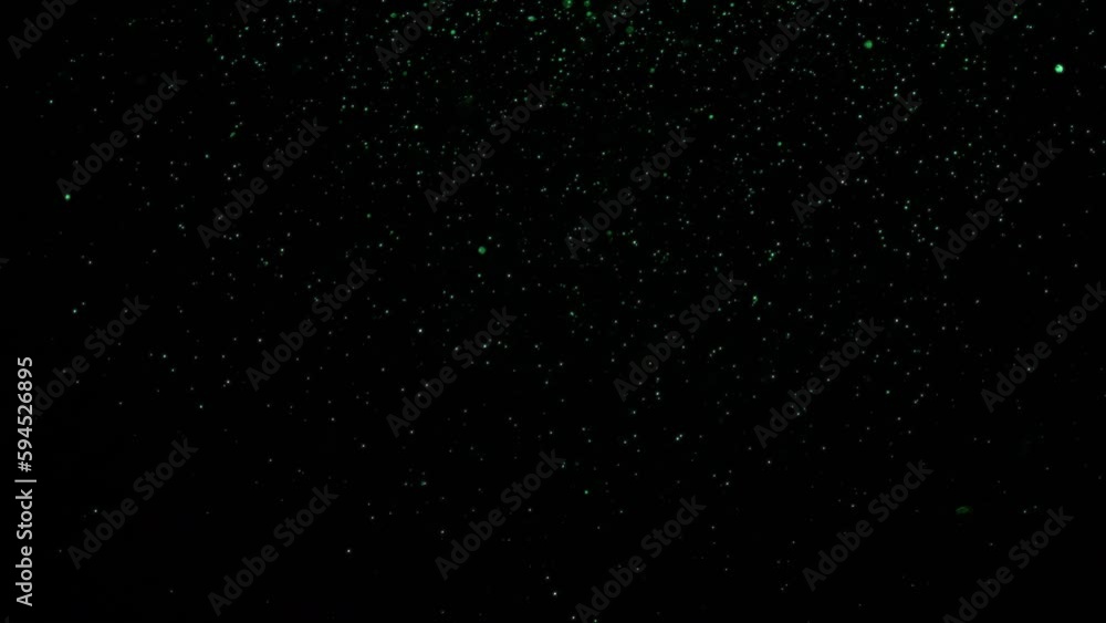 Green particles falling slowly from right to left over a black background. Isolated overlay.