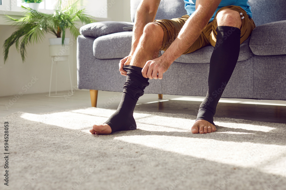Man wears compression stockings due to varicose or recovery after