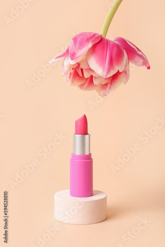 Decorative plaster podium with lipstick and tulip flower on beige background