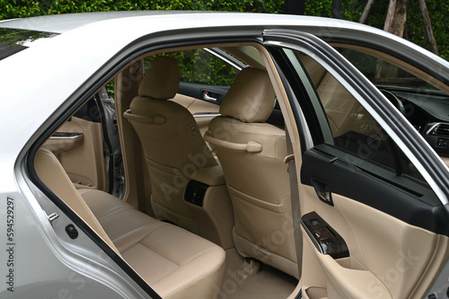 inside the back seat The passenger seat is wide and clean. Leather interior design, car passenger and driver seats, clean, angle view side, sunroof solar, buttons, dashboard, nappa leather, beige. © chatchai
