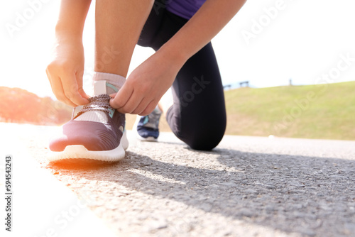 Active healthy woman tying running shoes, jogging runner healthcare and well being concept.