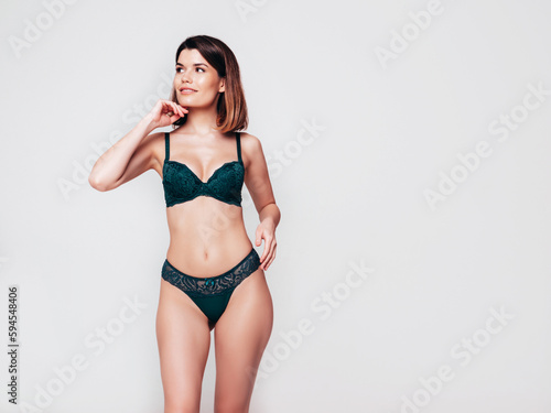 Young beautiful sexy woman in green lace lingerie. Carefree confident model wearing green underwear. Hot brunette posing on white wall in studio. Perfect body. Slim and fit. Isolated © halayalex